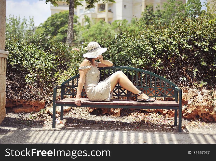 Girl in a hat on a park bench resting