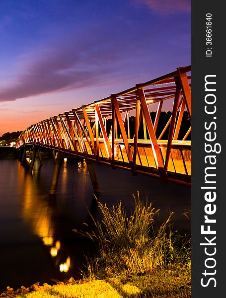 Lit bridge at dawn with colorful sky background.