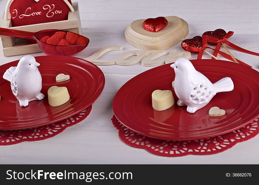 Two ceramic white birds on red plates, ornaments on light background. Two ceramic white birds on red plates, ornaments on light background