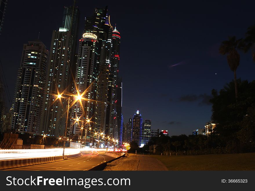 View of Dubai city skyline at dusk with streaks of light caused by moving vehicles. View of Dubai city skyline at dusk with streaks of light caused by moving vehicles.