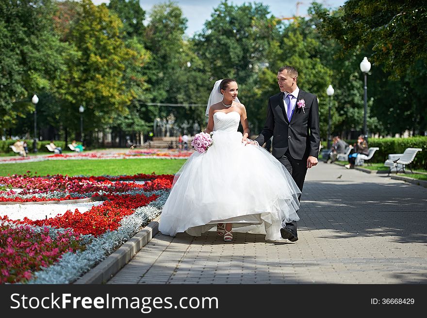 Happy groom and bride on wedding walk in park