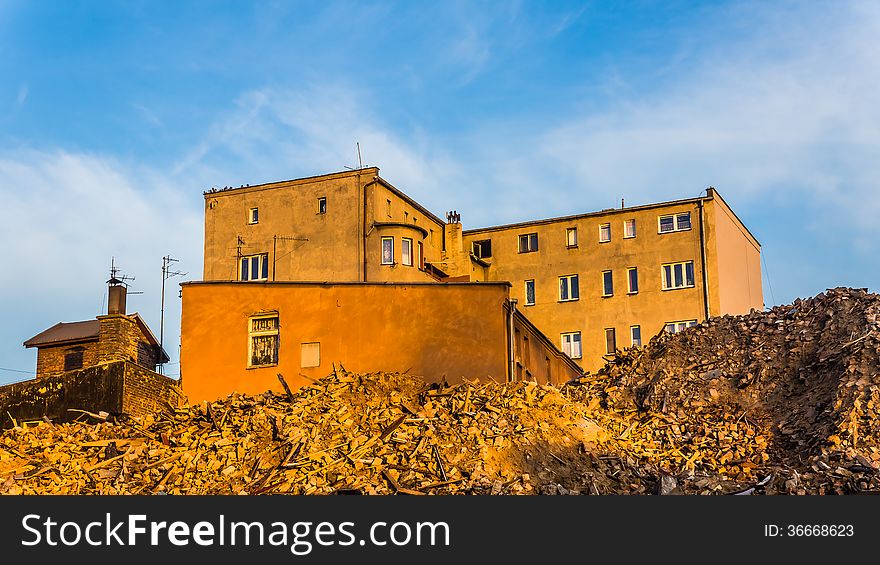 Debris remained after demolishing an old tenement with sun-flooded residential buildings in the background, in Katowice, Silesia region, Poland.