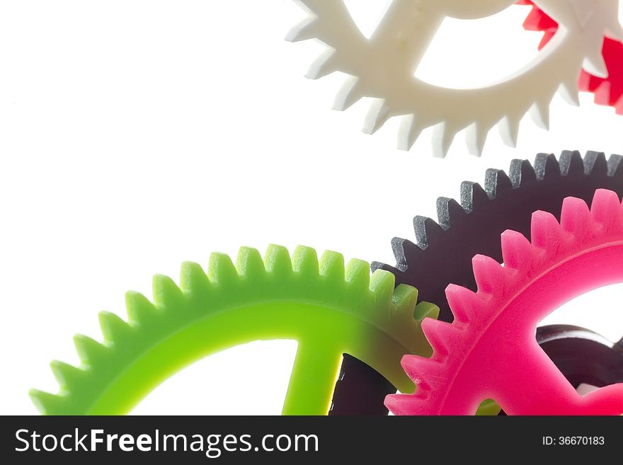 Full-frame background multicolor clockwork cogs isolated on white with selective focus