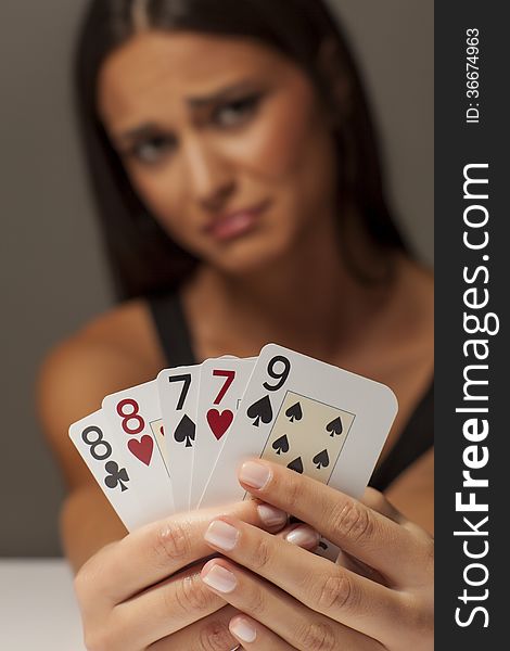 Unhappy girl holding a bad hand of playing cards