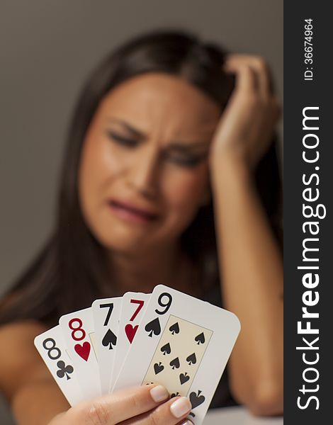 Unhappy girl holding a bad hand of playing cards