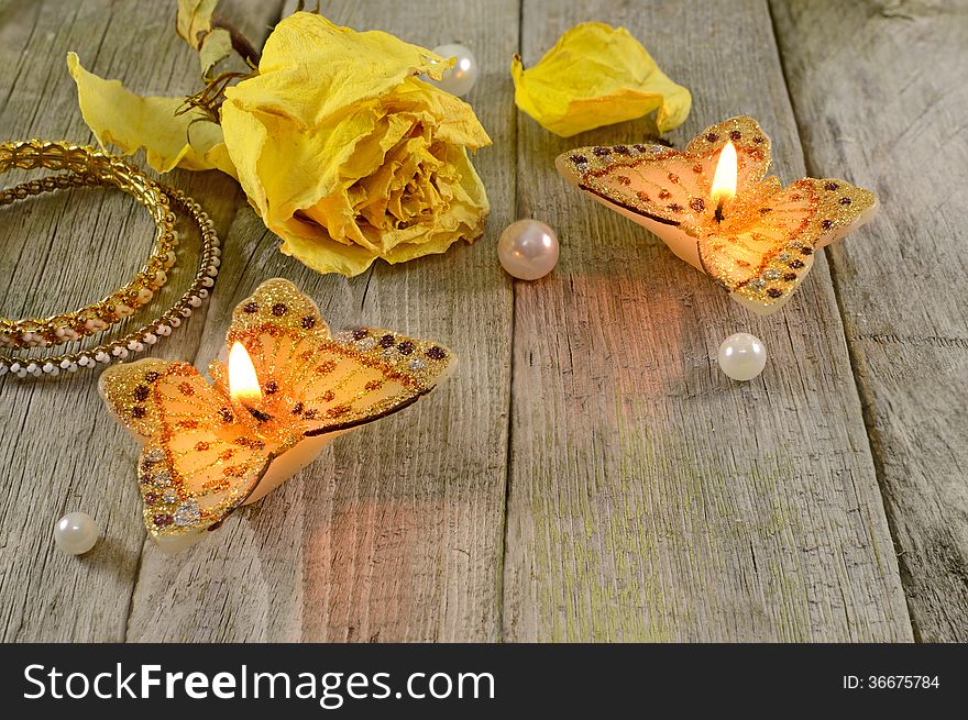 Two butterfly candles with dry rose and jewelry on wood. Two butterfly candles with dry rose and jewelry on wood