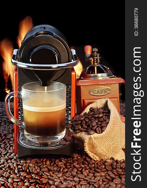 Coffee maker with mug of espresso surrounded by coffee beans, grinder and fire on the background XXXL. Coffee maker with mug of espresso surrounded by coffee beans, grinder and fire on the background XXXL