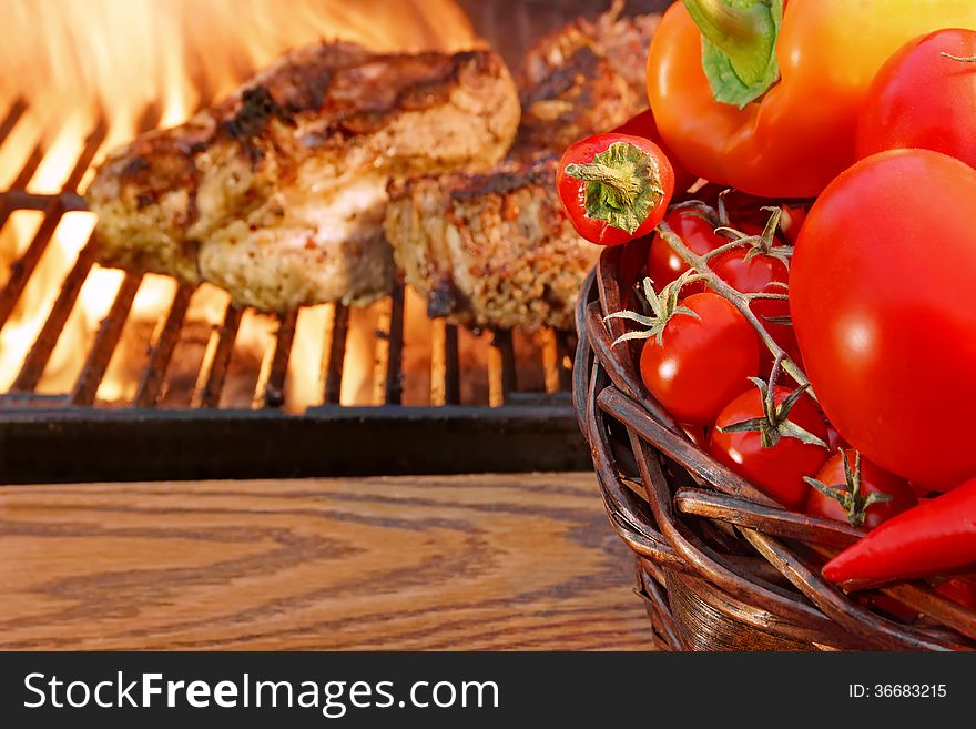 Vegetables in the basket and Glowing BBQ Grill with Roasted Meat in the background. Vegetables in the basket and Glowing BBQ Grill with Roasted Meat in the background