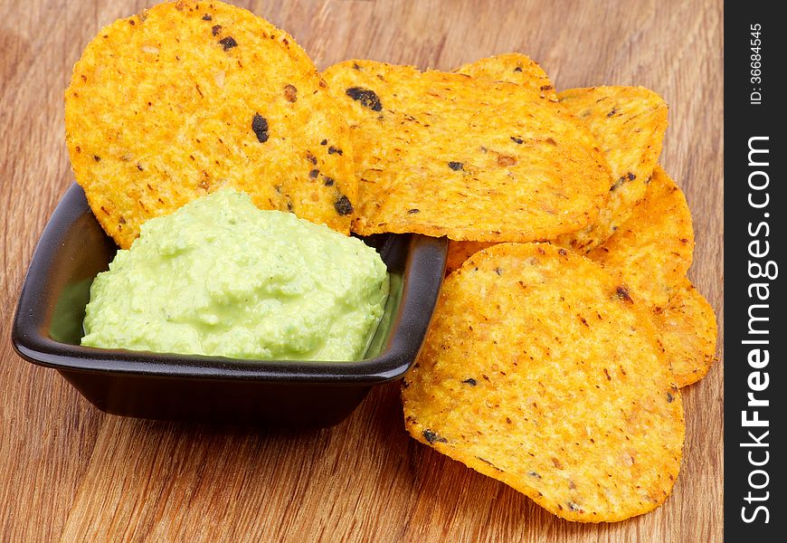 Arrangement of Tortilla Chips and Guacamole Sauce in Black Bowl closeup on Wooden background