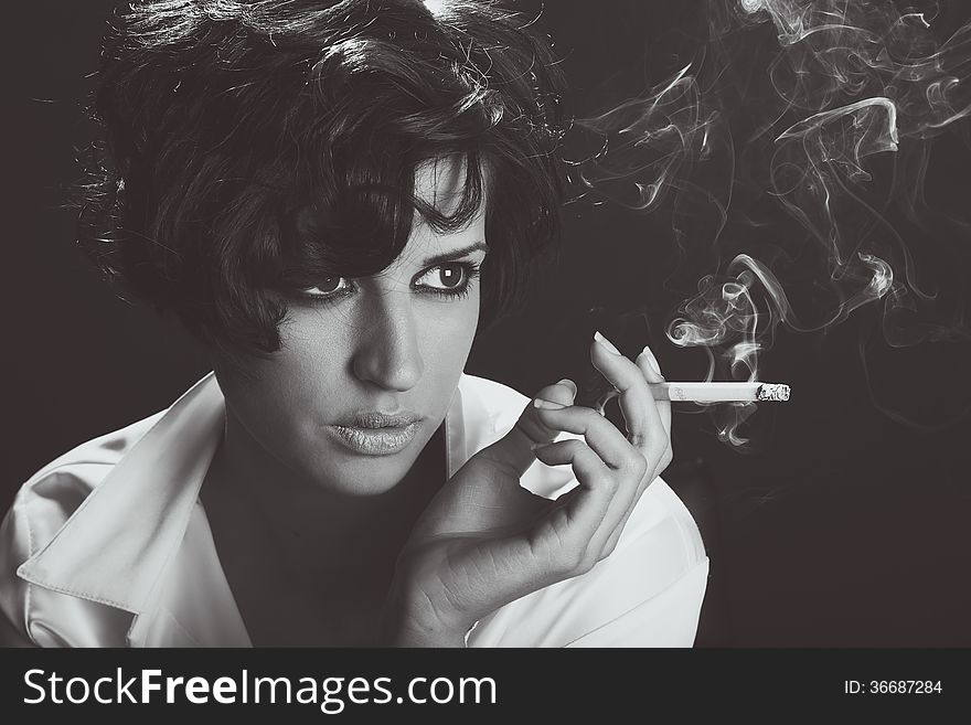 Elegant Brunette Woman Smoking A Cigarette On Black Background