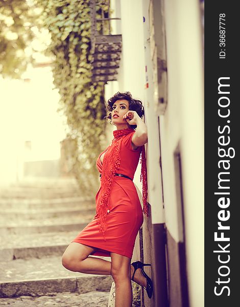 Portrait of a pretty woman, vintage style, in urban background, wearing a red dress. Portrait of a pretty woman, vintage style, in urban background, wearing a red dress