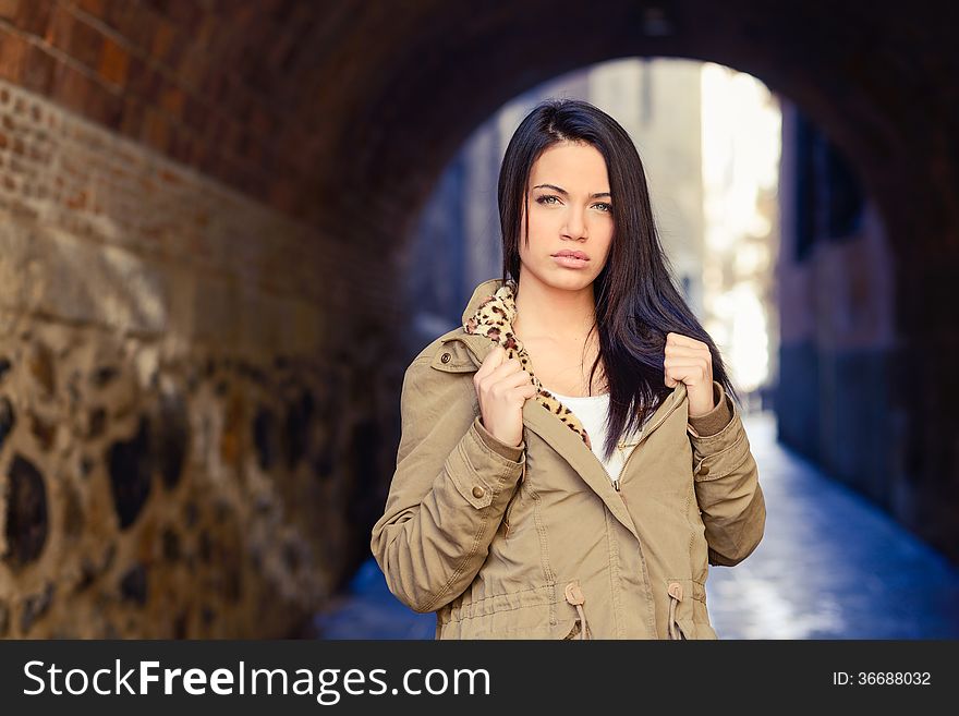 Portrait of brunette young woman with green eyes, wearing a coat, in urban background. Portrait of brunette young woman with green eyes, wearing a coat, in urban background