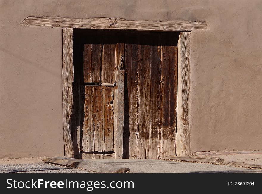 A picture of an old wooden door on an old adobe building. A picture of an old wooden door on an old adobe building.
