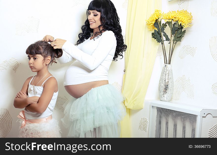 Beautiful pregnant woman with her little funny daughter