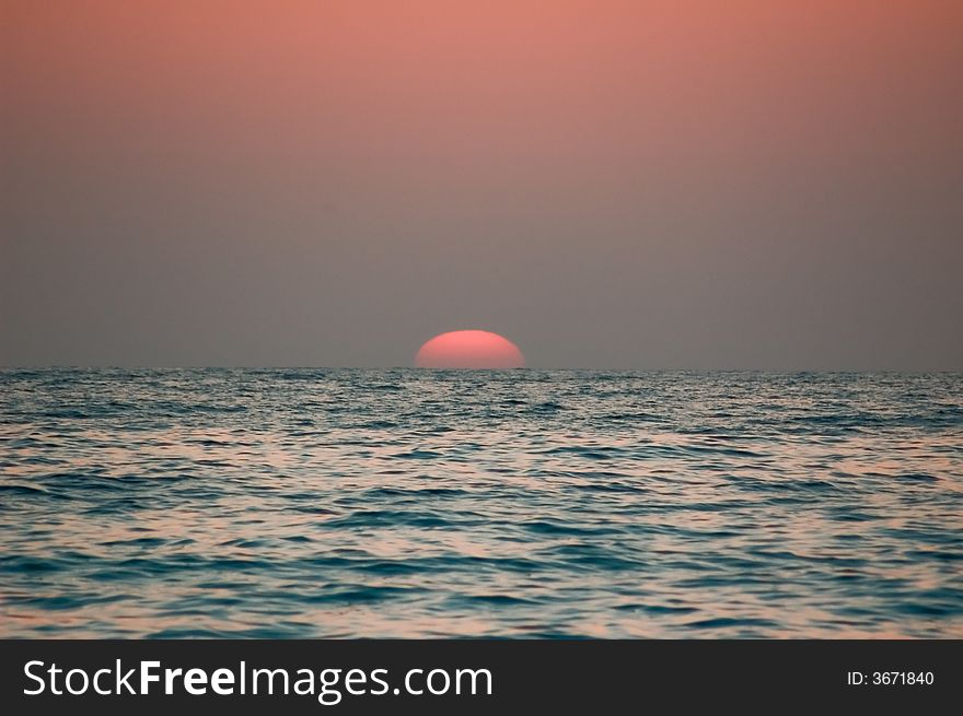 Photo of red sun sets beyond the Mediterranean sea. Photo of red sun sets beyond the Mediterranean sea