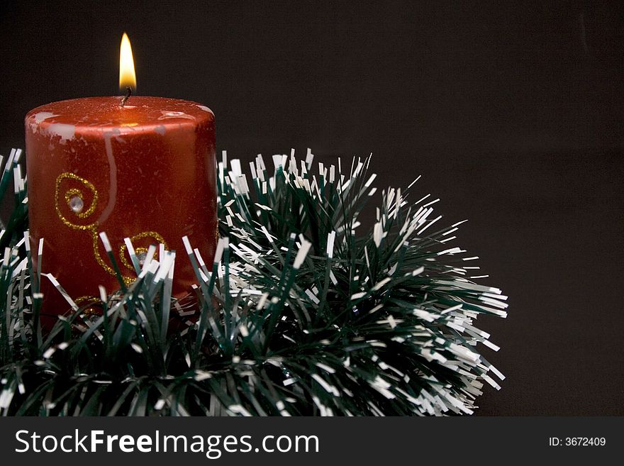 Red candle with green decoration on the black background