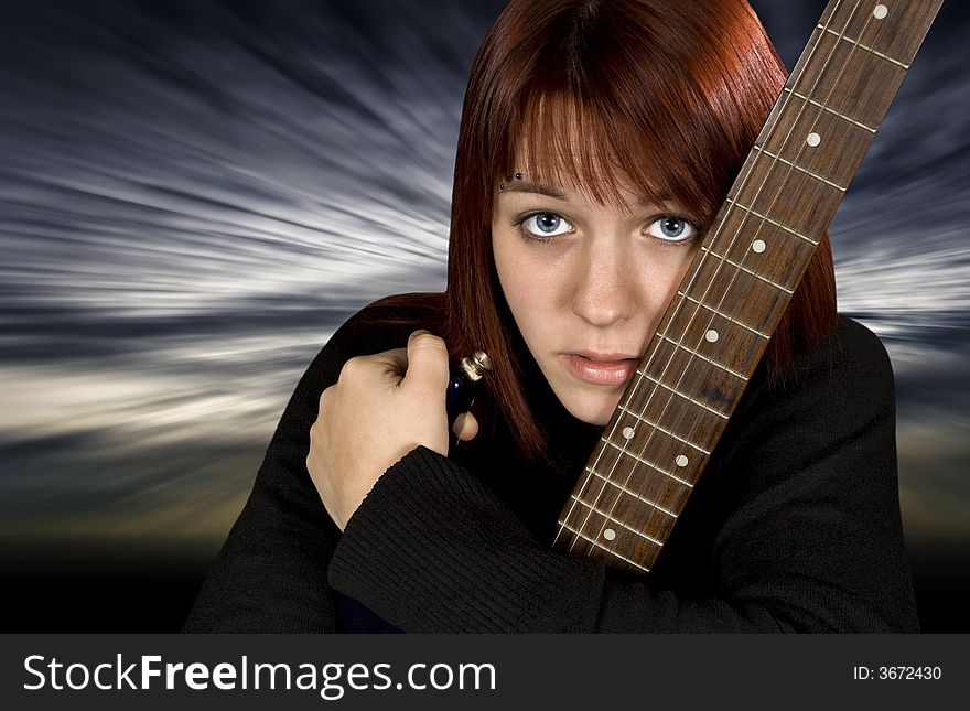 Depressed redhead girl protecting her guitar with a dramatic background. Depressed redhead girl protecting her guitar with a dramatic background.