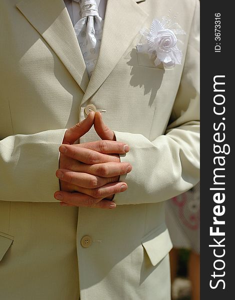 Photo of a bridegroom hands with fingers interlaced in pending