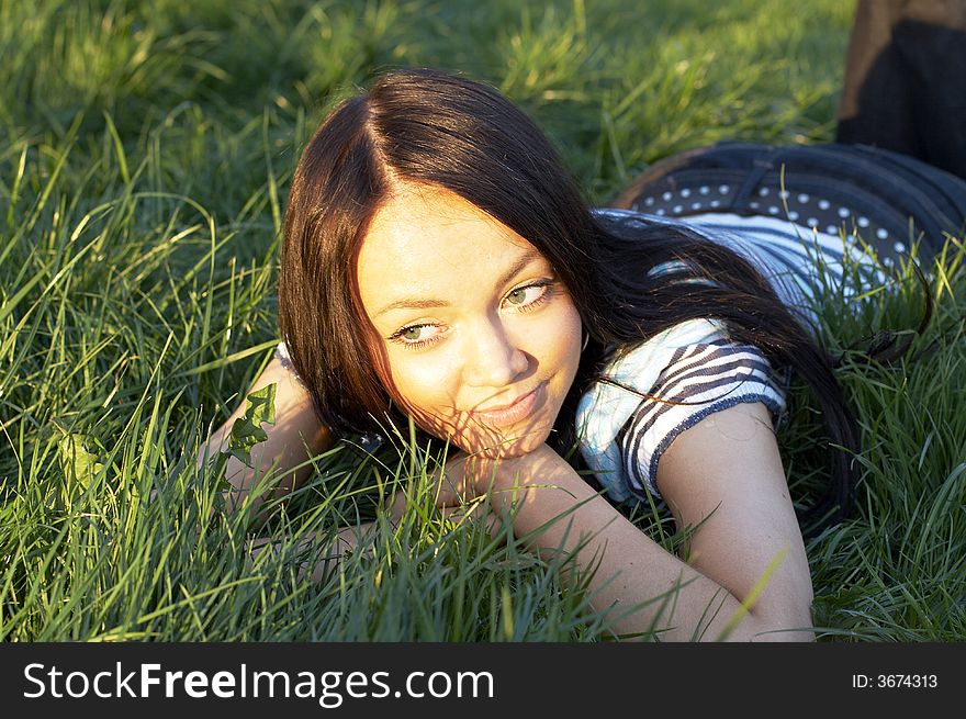 Teen girl lays on a grass