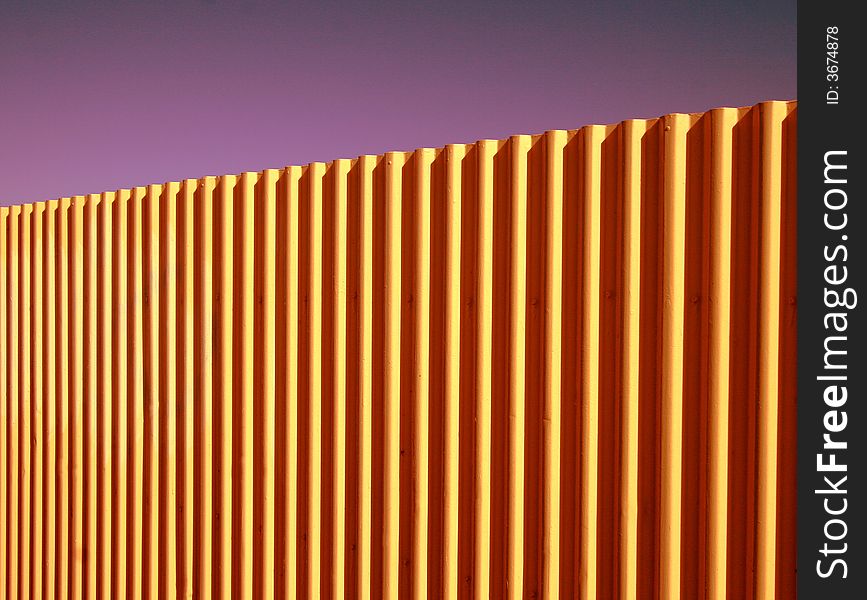 Bright coloured background of corrugated fence against a clear purple haze.