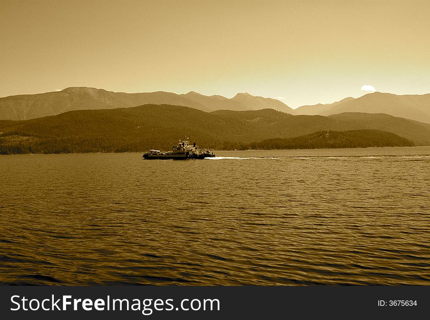 Sepia view of boat crossing lake in British Columbia, Canada
