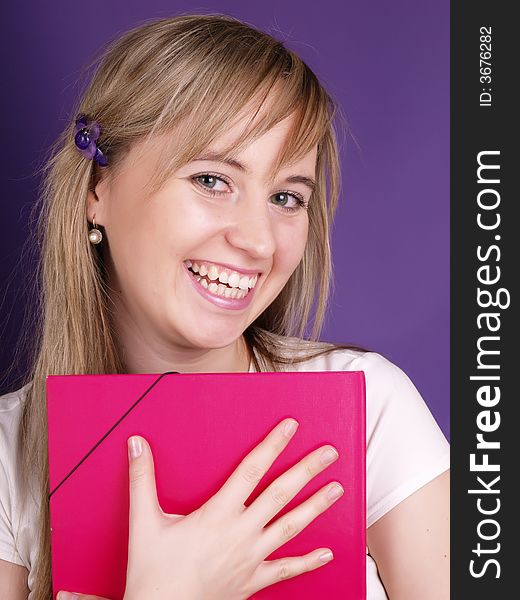 Smiling young woman with pink folder on the purple background.