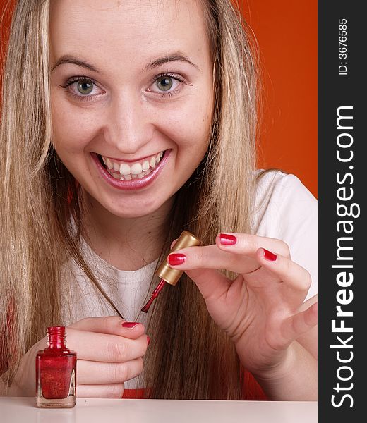 Smiling woman applying nail polsih