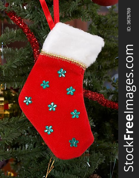 A red christmas stocking hanging on a christmas tree. A red christmas stocking hanging on a christmas tree