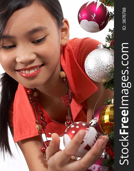 A young girl holding a bauble on a christmas tree