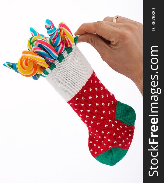 A hand holding a christmas stocking with lollipop candies inside. A hand holding a christmas stocking with lollipop candies inside