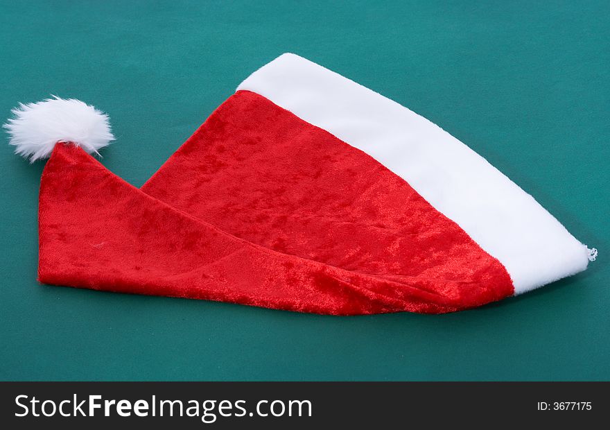 A red christmas hat over a green background