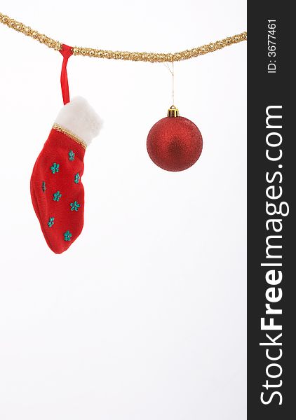 A christmas stocking and a bauble hanging over a white background