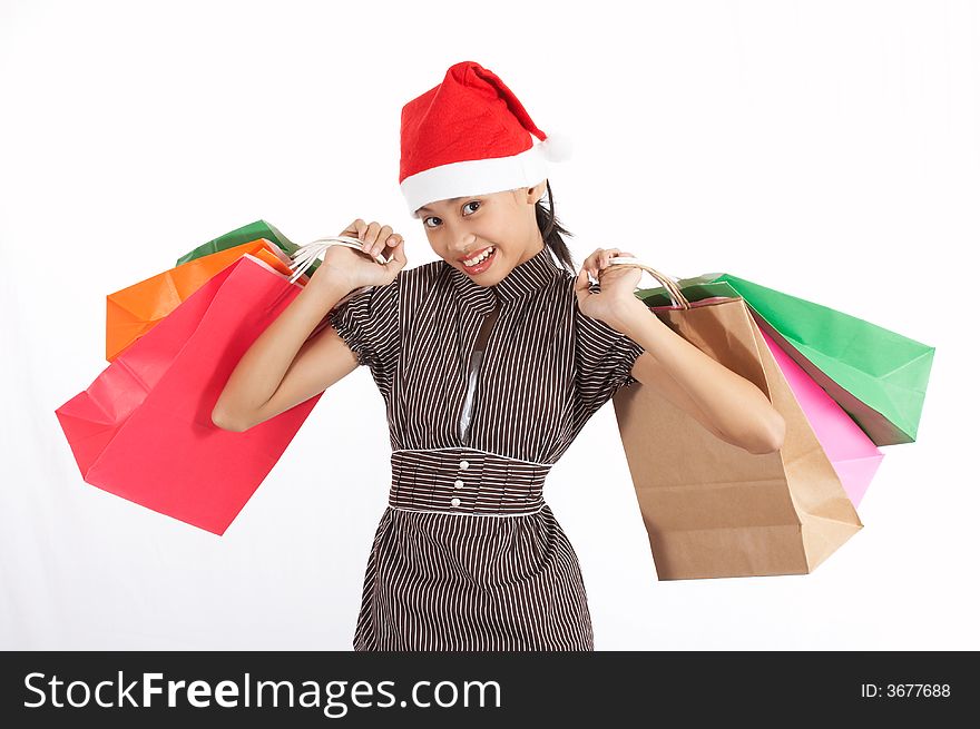 A girl wearing a christmas hat while holding some shopping bags