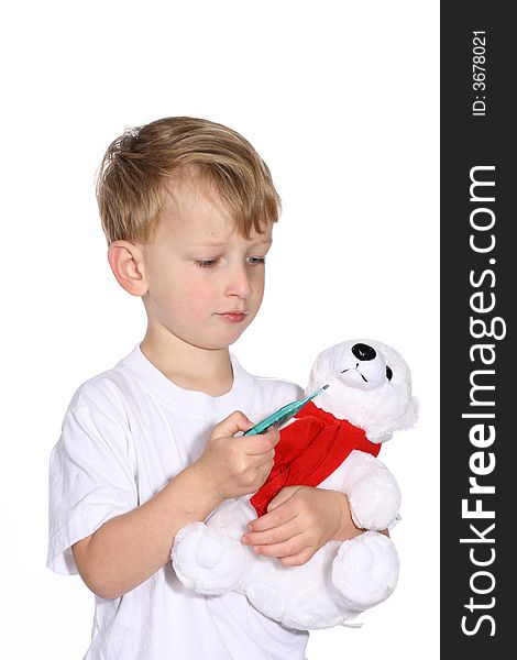 Cute young boy using a thermometer on his stuffed bear. Cute young boy using a thermometer on his stuffed bear