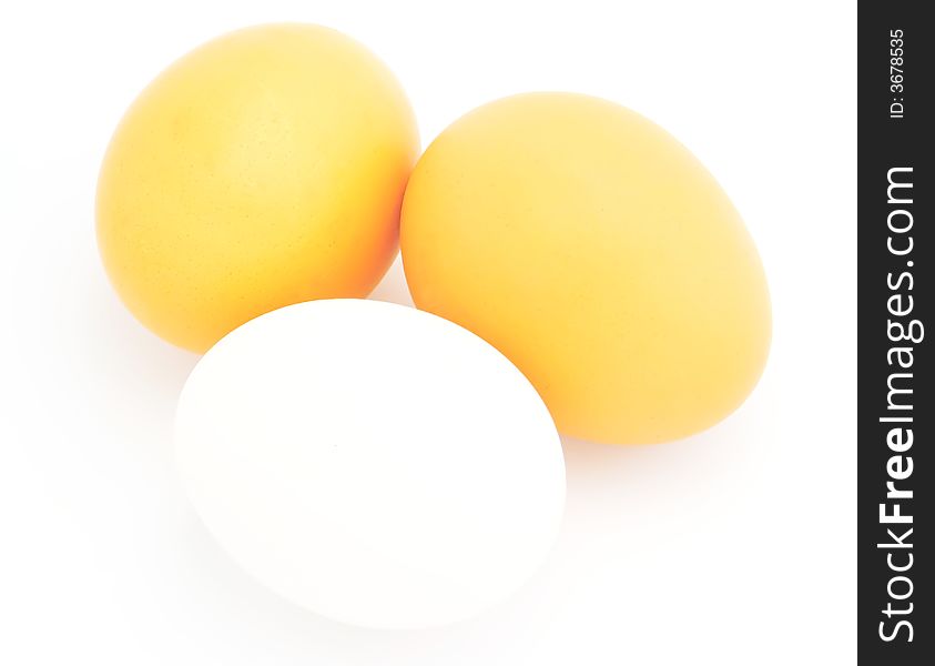 Three chicken eggs - two yellow and one white. Object on a white background. Three chicken eggs - two yellow and one white. Object on a white background.