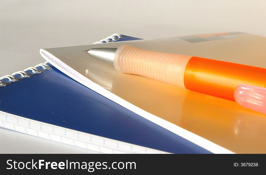 blue notebook, orange notebook and orange pen. blue notebook, orange notebook and orange pen