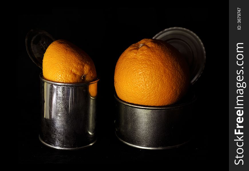 Oranges in cans over black background. Oranges in cans over black background
