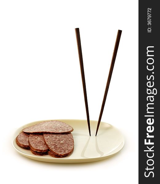 Chopsticks standing in a plate with sausage slices. Chopsticks standing in a plate with sausage slices