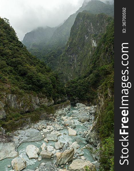 Rocky river between steep and lush mountains