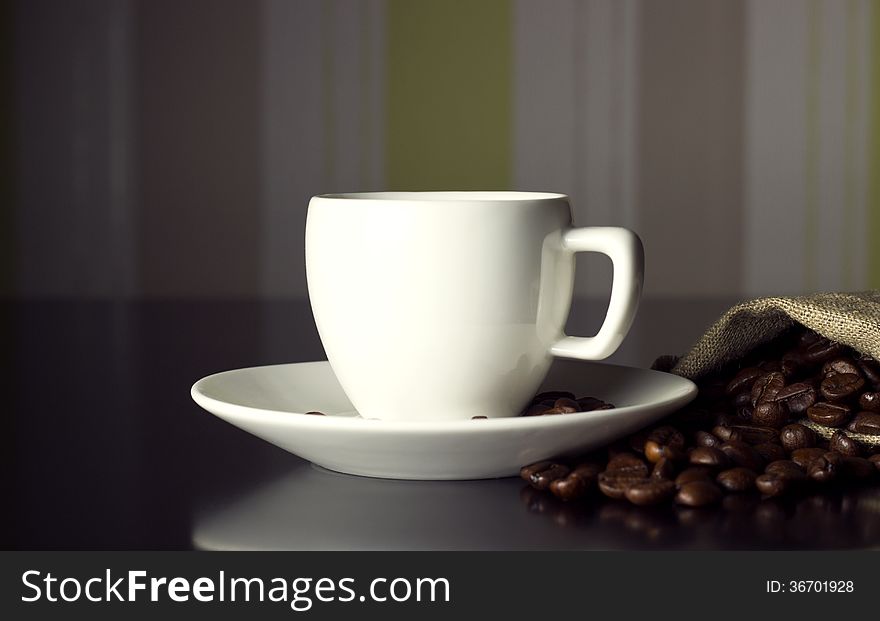 White cup with coffee beans on black table. White cup with coffee beans on black table