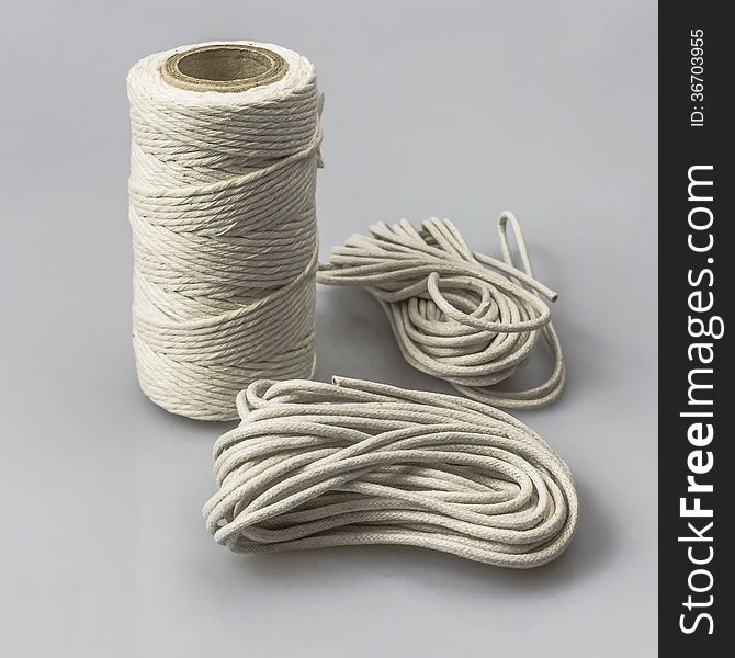 A spool with thread and strings on gray background. A spool with thread and strings on gray background.