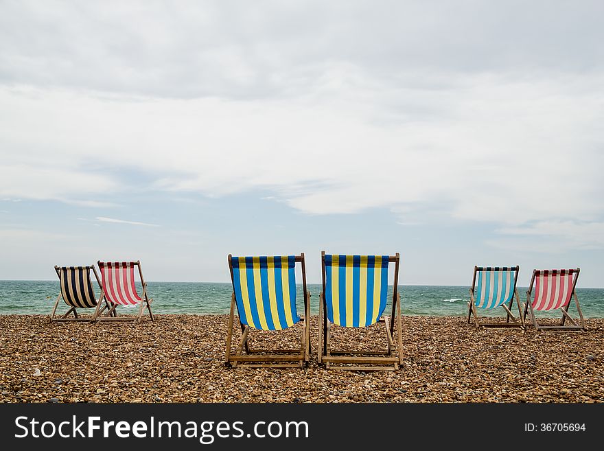 6 stripy deck chairs on a shingle beach in Brighton, Southwest England. Taken on an overcast day. 6 stripy deck chairs on a shingle beach in Brighton, Southwest England. Taken on an overcast day