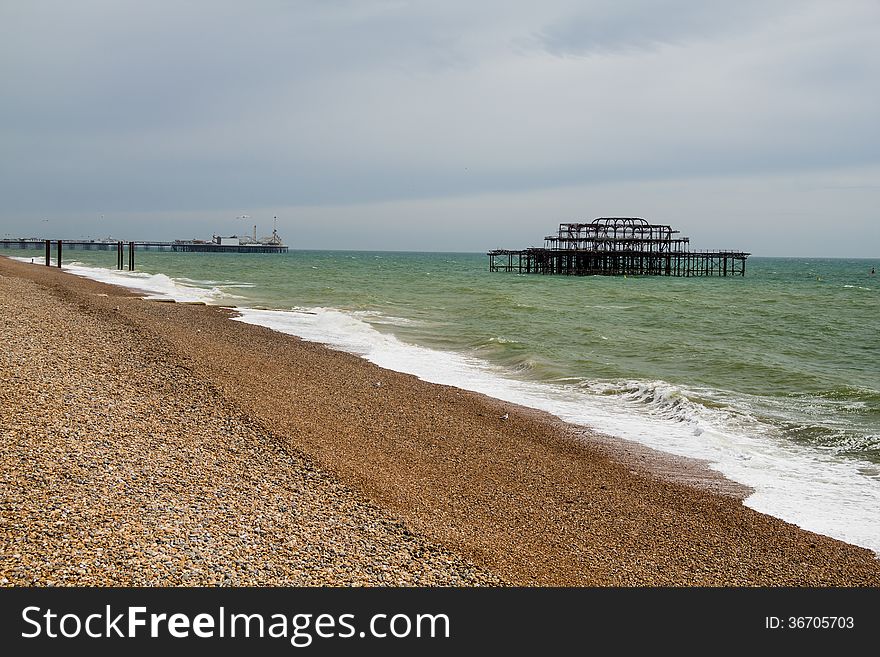 Landscape shot of the ruins of the West Pier on Brighton Beach with the shingle beach in the foreground and Palace Pier in the background. Landscape shot of the ruins of the West Pier on Brighton Beach with the shingle beach in the foreground and Palace Pier in the background