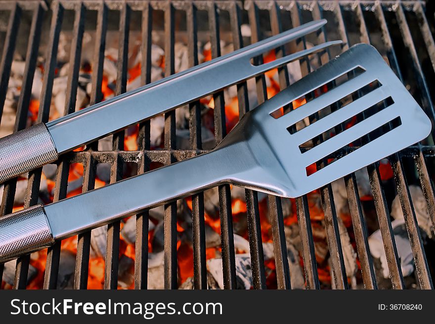 BBQ facilities and Spatula with fork on a Hot Cast Iron Grill. BBQ facilities and Spatula with fork on a Hot Cast Iron Grill