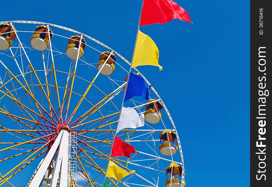 Ferris wheel and colorful flags against blue sky