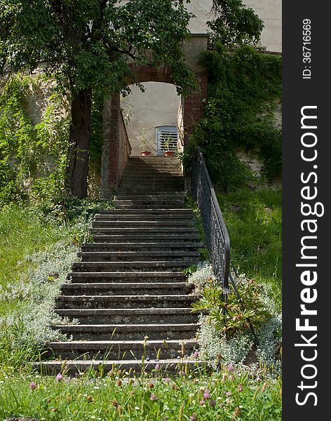 Steps with wrought iron railing, rising from grass, leading to a brick arch. Steps with wrought iron railing, rising from grass, leading to a brick arch