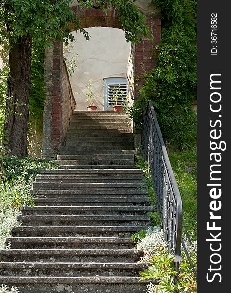 Steps with wrought iron railing, rising from grass, leading to a brick arch. Steps with wrought iron railing, rising from grass, leading to a brick arch