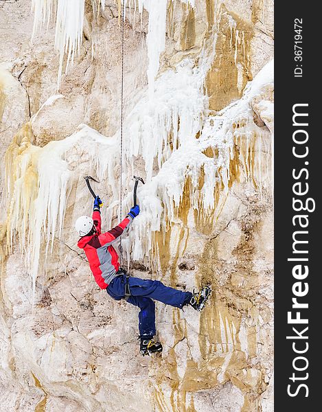 Young man climbing the ice using ice axe