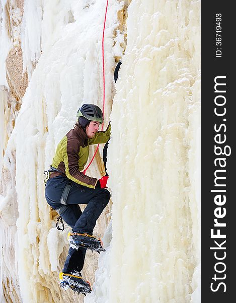 Young man climbing the ice using ice axe