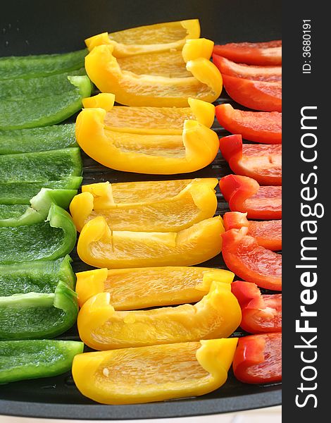 Colorful rows of green, yellow and red capsicum strips prepared for cooking on a pan. Colorful rows of green, yellow and red capsicum strips prepared for cooking on a pan